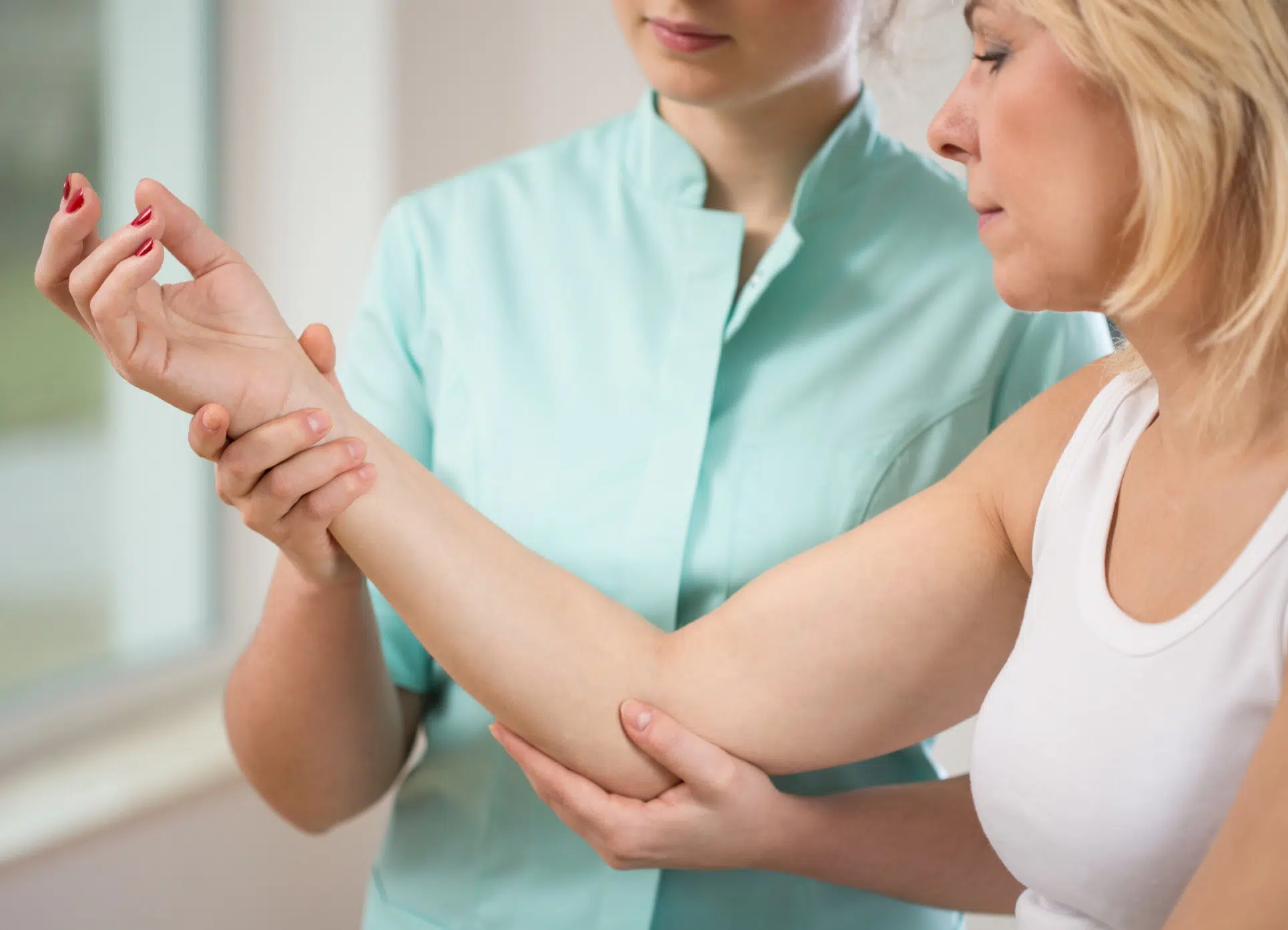 Médecin en train d'examiner le bras d'une femme - Compression du nerf ulnaire au coude | Leman hand Clinic Genève
